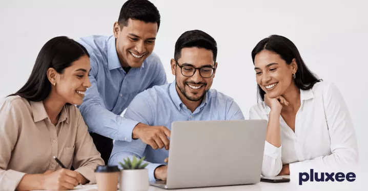 Equipo de trabajo colaborando frente a una laptop con actitud positiva y compromiso laboral