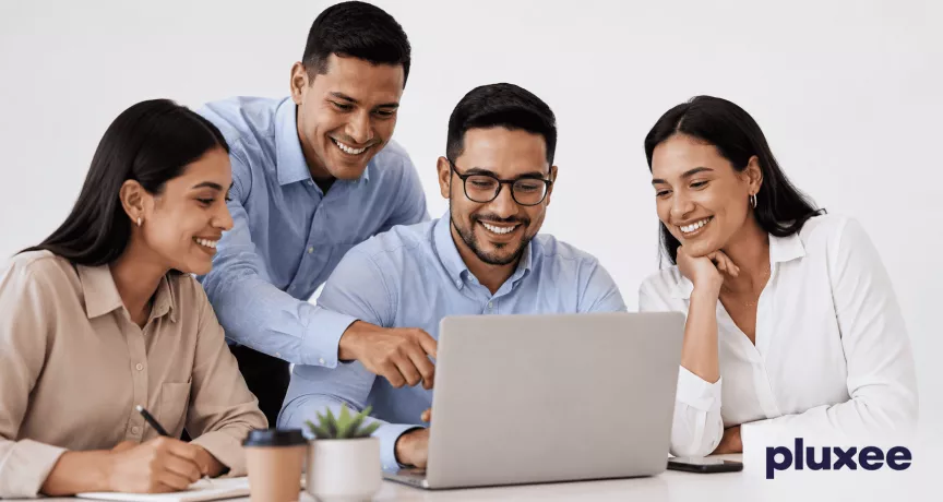 Equipo de trabajo colaborando frente a una laptop con actitud positiva y compromiso laboral