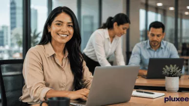 Mujer profesional sonriendo en su espacio de trabajo junto a su equipo, representando el compromiso laboral y la colaboración en la oficina